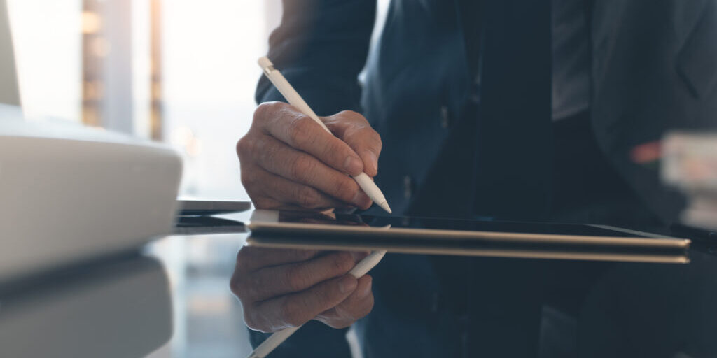 Imaged depicts a person signing a contract.