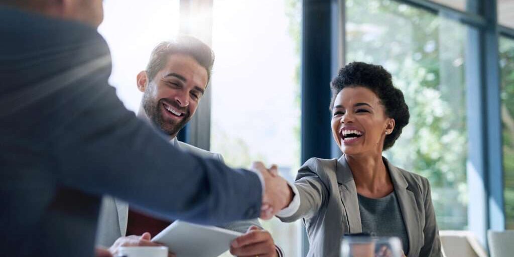 Meeting, partnership and business people shaking hands in the office for a deal, collaboration or onboarding. Diversity, professional and employees with handshake for agreement, welcome or greeting